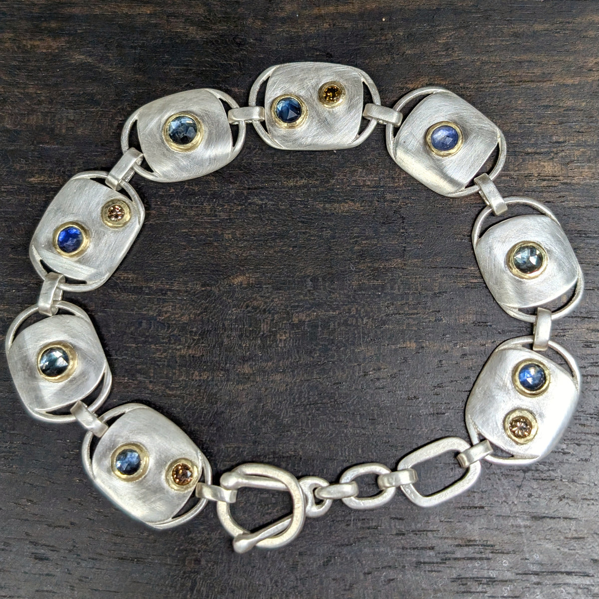 Custom bracelet with sapphires and diamonds bezel set in 18k gold on argentium silver.  Completely hand fabricated and very comfortable.