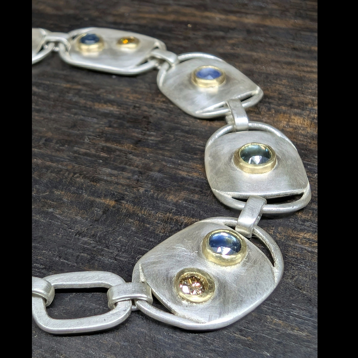 Custom chain bracelet with blue and teal rose cut Montana sapphires and cognac diamonds set in 18k gold on argentium silver