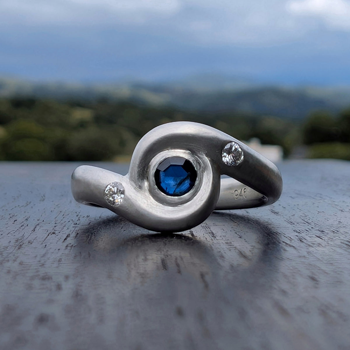 A forged swirl ring with a portrait cut Australian sapphire and flush set  lab grown diamonds