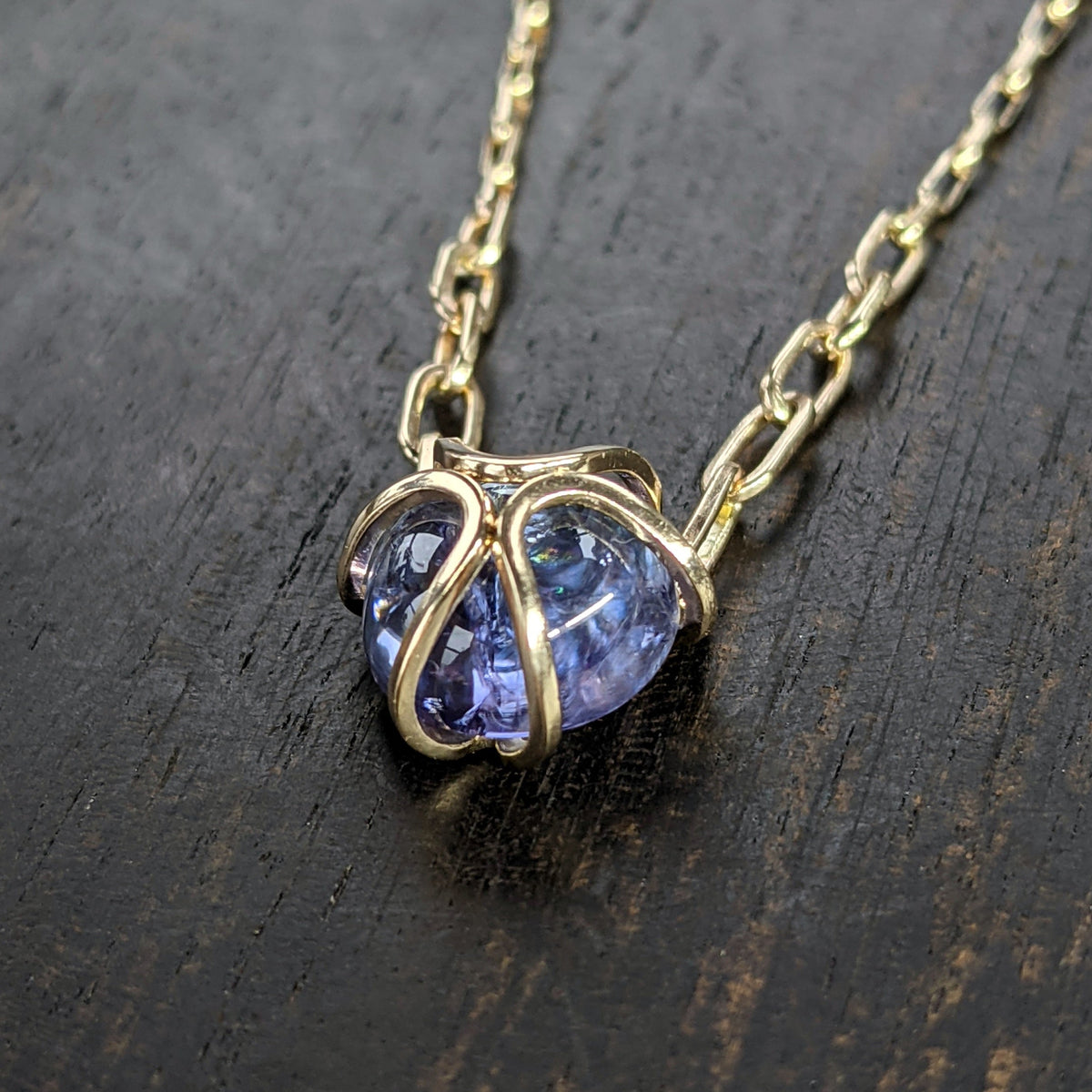 14K Iris Necklace with an unheated mermaid tanzanite cabochon and graduated links connecting the pendant to the chain.